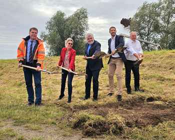 Erster Spatenstich am Aland: Minister Prof. Dr. Armin Willingmann und LHW-Direktorin Martina Große-Sudhues sowie weitere Vertreter haben Spaten in der Hand und schippen damit Erde. Sie stehen am Deich bei gutem Wetter. 