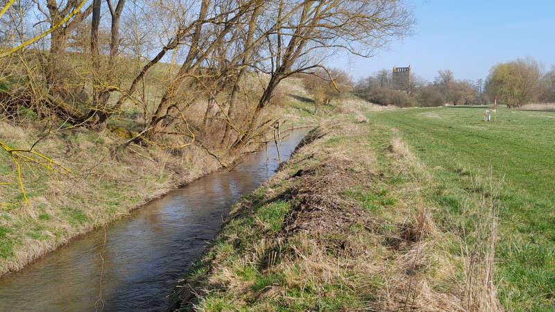 Der Fluss Beber bei Hundisburg mit der Kirchturmruine Nordhusen im Hintergrund