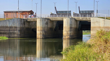 Blick auf das Aland-Abschlussbauwerk, das sich im Wasser des Alands spiegelt. 