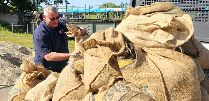 Ein Mann lädt im Rahmen einer Wasserwehrschhulung einen Sandsack auf die Ladefläche eines Multicars