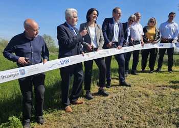 Vertreter von Landesministerien und Behörden in Sachsen-Anhalt und Tghüringen durchschneiden zur offiziellen Deichfertigstellung symbolisch ein Band. 
