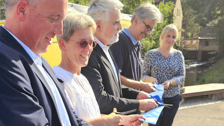 Umweltminister Prof. Dr. Armin Willingmann schneidet gemeinsam mit Vertretern des LHW und der Politik das Band durch. Die Menschen lächeln. Das Foto ist seitlich aufgenommen.