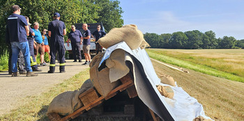 Foto von einer Wasserwehrschulung. Im Vordergrund eine Deicherhöhung mit Europaletten, dahinter die Schulungsteilnehmer.